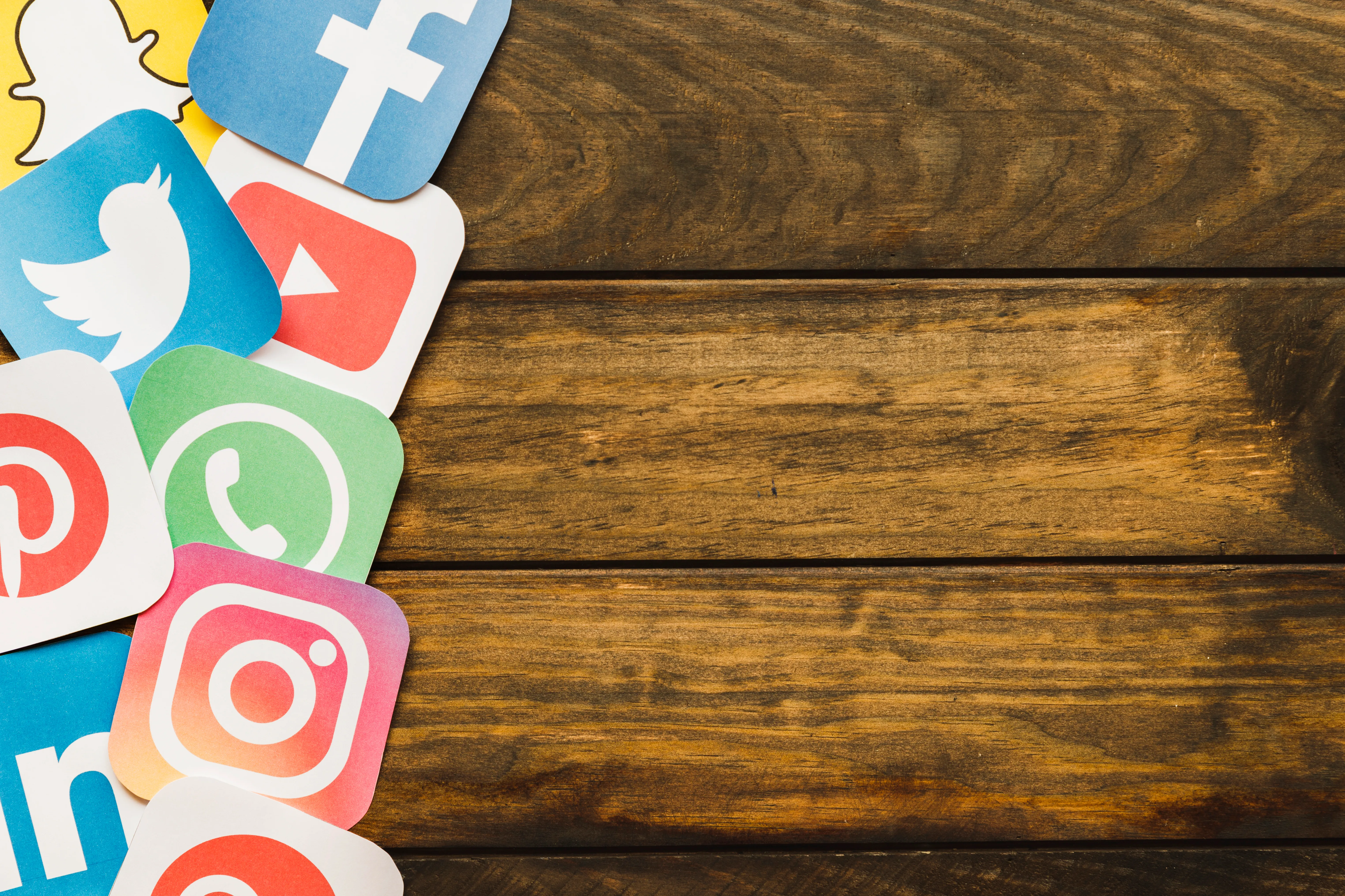 there are many social media logo images on the left side of the wooden table