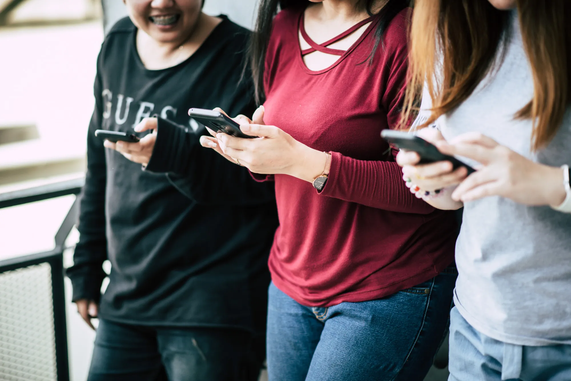 three women standing on the roadside using mobile phones