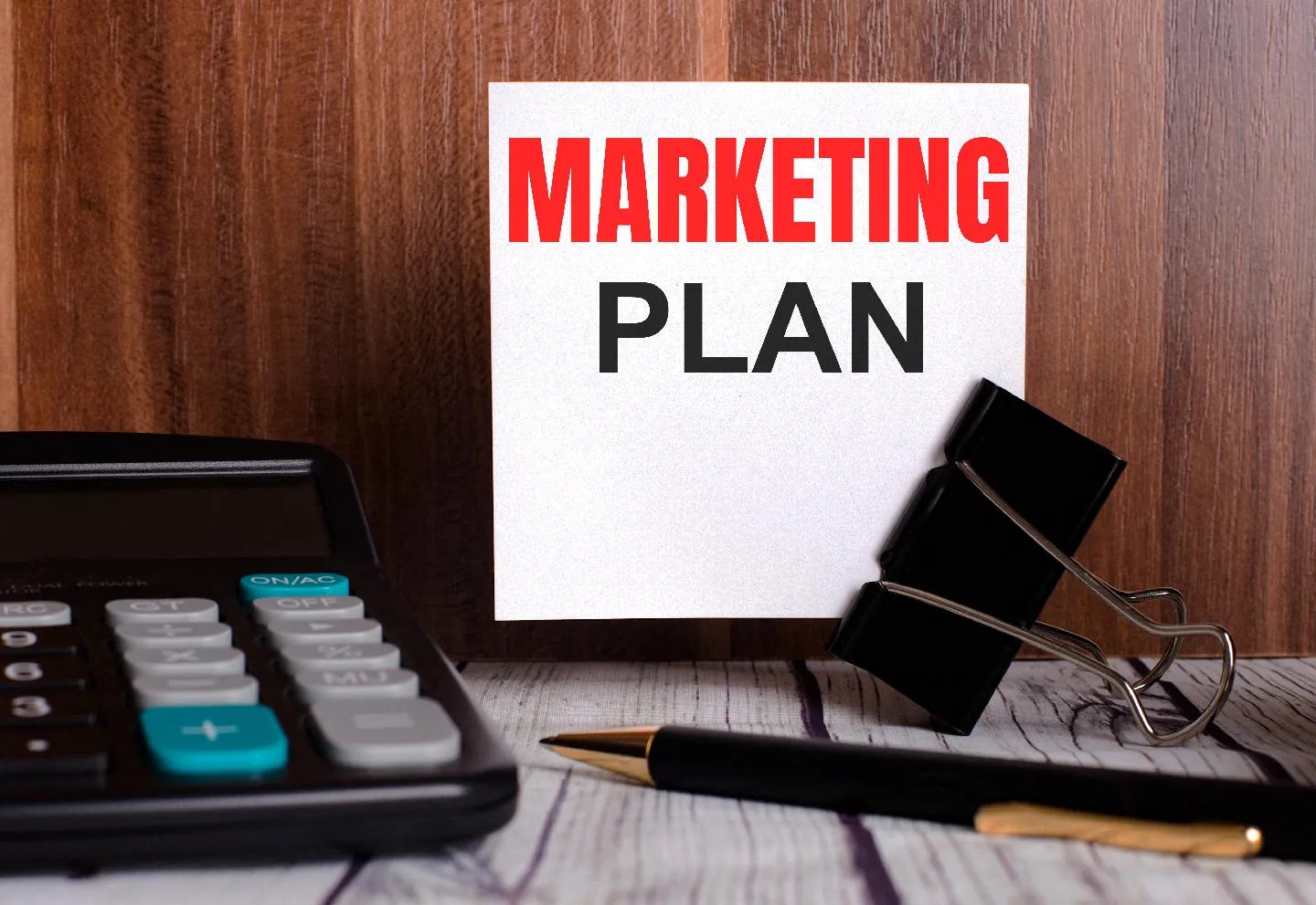 "MARKETING PLAN" sign on desk.