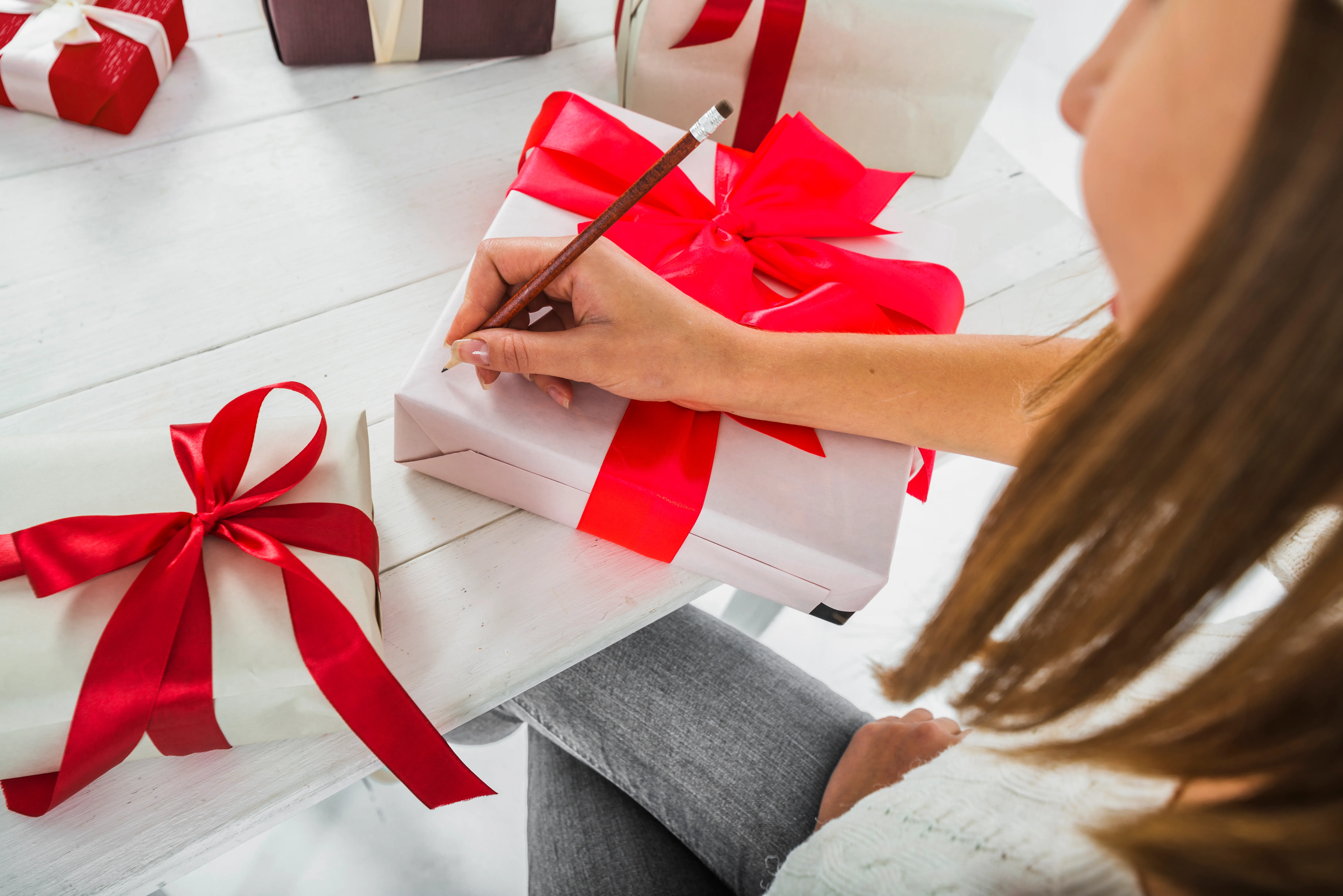 Person writing on gift - wrapped box.
